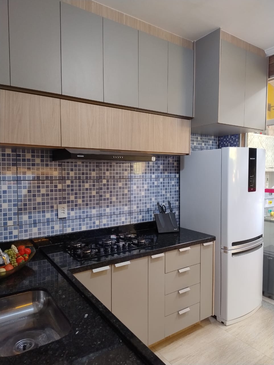 Cozinha planejada com armários em tons claros e bancada em granito